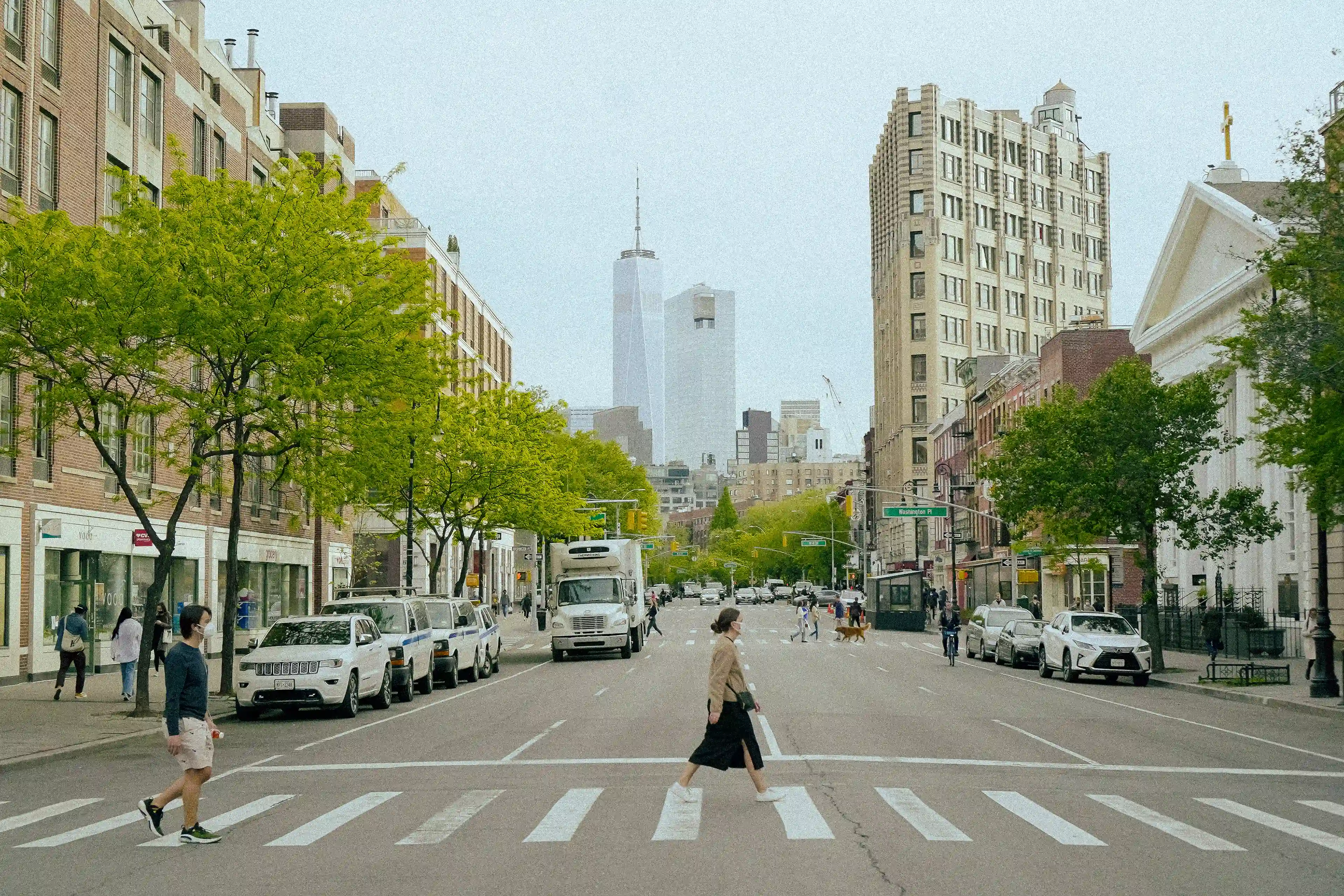 A tree-lined Manhattan street looking toward One World Trade Center